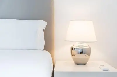 a bed and a lamp on a night stand next to a bed at GuestReady - Modern Duplex, Neo-Classical Building in Porto