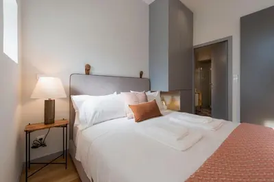 a bedroom with a large white bed and a lamp at Tripas-Coração, Almada Charming City Center in Porto