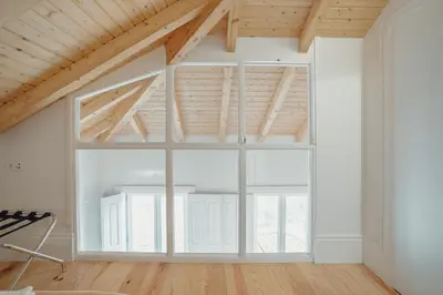 a large window in a room with white walls and wooden ceilings at Downtown Clerigos Duplex With River View by Vacationy in Porto