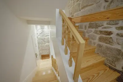 a wooden staircase in a house with a stone wall at Downtown Clerigos Duplex With River View by Vacationy in Porto