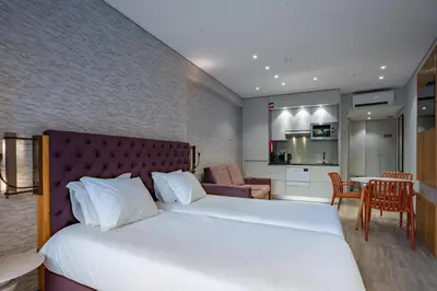 a bedroom with a large bed and a kitchen at Smartr Porto Gaia & Spa in Vila Nova de Gaia