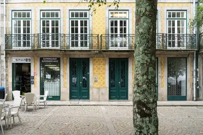 a building with green doors and tables and chairs at Virtudes Flat in Porto