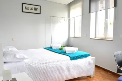 a bedroom with a white bed with a blue blanket on it at Casa do Mirante in Porto