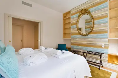 a bedroom with a white bed with a mirror on the wall at BOUTIQUE Rentals-Isabella Ribeira Apt great views in Porto