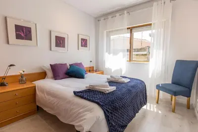 a bedroom with a bed and a blue chair at Metro Lapa House with sunny balcony and A/C in Porto