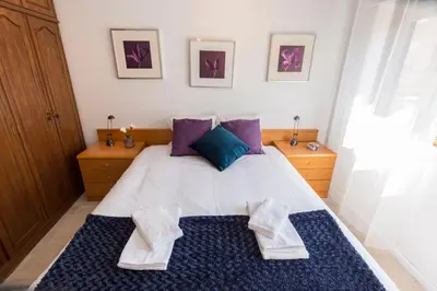 a bedroom with a large bed with purple and blue pillows at Metro Lapa House with sunny balcony and A/C in Porto
