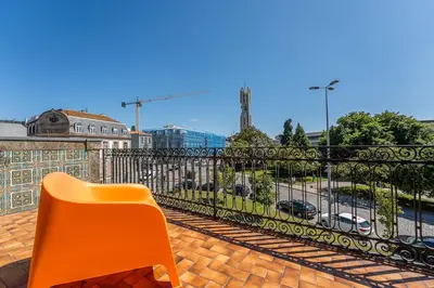 an orange chair sitting on a balcony with a fence at GuestReady - Amazing stay near Cedofeita Church in Porto