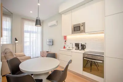 a white bedroom with a bed and a window at Liiiving in Porto - Sweet Sunlight Apartment in Porto
