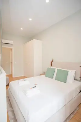 a white bedroom with a bed and a kitchen at Liiiving in Porto - Sweet Sunlight Apartment in Porto