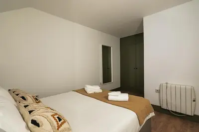 a white bedroom with a bed with two towels at Oporto family apartment in Porto