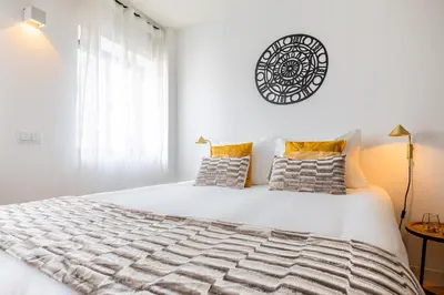 a white bedroom with a large white bed and a window at S. Lázaro Studio in Porto