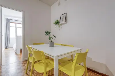 a dining room with a white table and yellow chairs at Travel & Live Alegria 248 in Porto