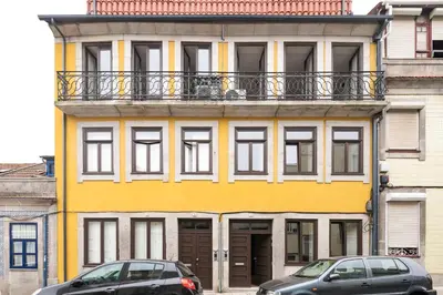 a yellow building with two cars parked in front of it at Bright Studio near Douro River - with Balcony in Porto