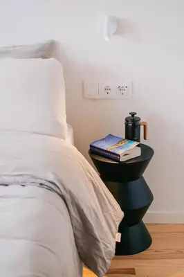 a bed with a night stand with a book on it at Gharb in Porto
