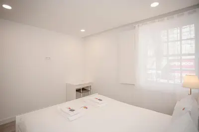 a white bedroom with a white bed and a window at Liiiving in Porto - Ribeira Riverside Apartment in Porto