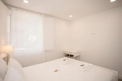 a white bedroom with a white bed and a window at Liiiving in Porto - Ribeira Riverside Apartment in Porto