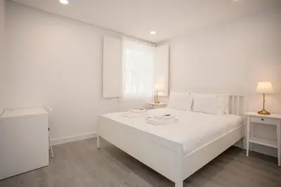 a white bedroom with a large white bed and two lamps at Liiiving in Porto - Ribeira Riverside Apartment in Porto