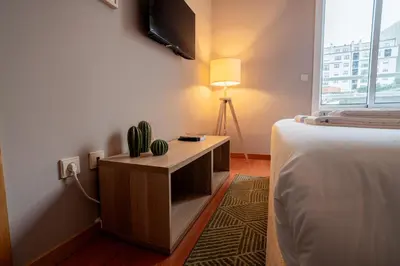 a bedroom with a bed and a desk with a tv at Mauve Studio perto do Metro, Cedofeita, Porto in Porto