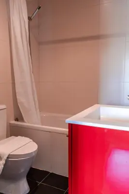 a bathroom with a white toilet and a red cabinet at Mauve Studio perto do Metro, Cedofeita, Porto in Porto