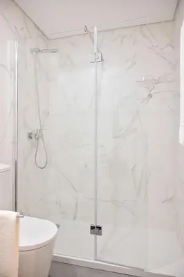 a bathroom with a shower with white marble walls at Strelitzia Apartment, by Bolhão Residences in Porto