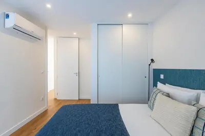 a bedroom with a white bed and a blue rug at Pestana Apartments - Premium in Porto