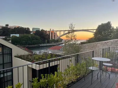 a balcony with a table and chairs and a sunset at 108MM House in Porto