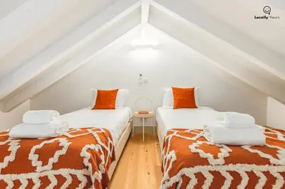 two beds with orange and white blankets in a attic at Locally Yours Flores Apartments in Porto