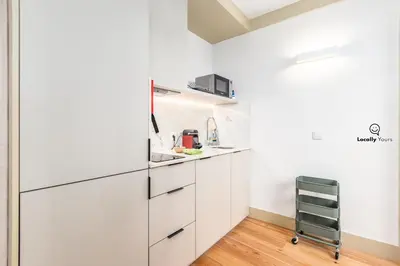 a kitchen with white cabinets and a cart in it at Locally Yours Flores Apartments in Porto