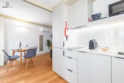 a kitchen with white cabinets and a dining room with a table at Locally Yours Flores Apartments in Porto
