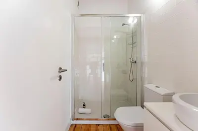 a white bathroom with a shower and a toilet at D. João IV Apartments by LovelyStay in Porto