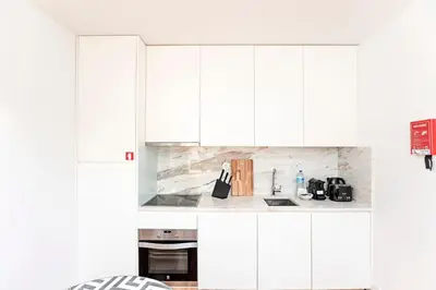 a white kitchen with white cabinets at D. João IV Apartments by LovelyStay in Porto