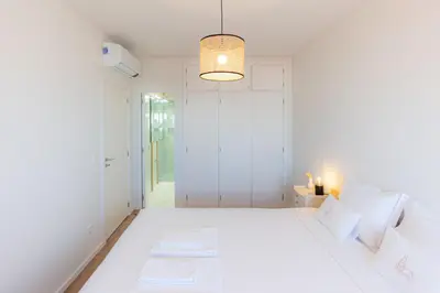 a white bedroom with a large white bed and a light fixture at Alegria Porto by We Do Living in Porto