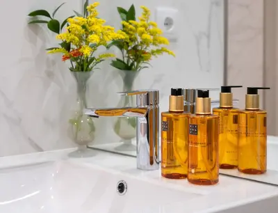a bathroom sink with four bottles of soap and flowers at Cactus Apartment, by Bolhão Residences in Porto