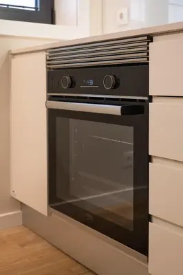 a black oven in a kitchen with white cabinets at Savannah Apartment, by Bolhão Residences in Porto