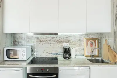 a kitchen with white cabinets and a sink and a microwave at Studio Duplex w/ AC In Praça República by LovelyStay in Porto