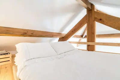 a white bed in a room with wooden beams at Studio Duplex w/ AC In Praça República by LovelyStay in Porto