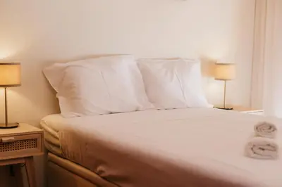 a bed with white pillows and two lamps in a room at Apartamento Santos Pousada in Porto