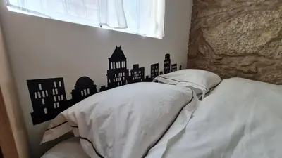 a bedroom with a bed with a city silhouette on the wall at KirasHouse in Porto