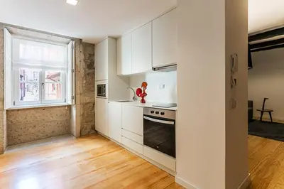 a kitchen with white cabinets and a window at Stay In Apartments in Porto