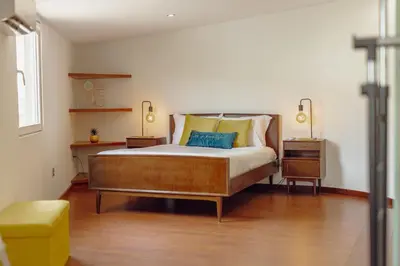 a bedroom with a large bed with two tables and a yellow stool at OPORTO GUEST Oliveira House in Porto