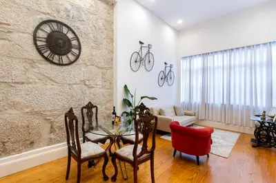 a living room with a table and chairs and a stone wall at Majestic Cafe - Porto City Center Modern Apartment in Porto