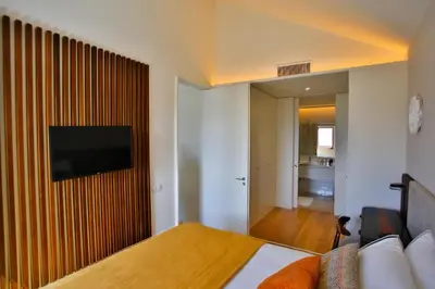 a bedroom with a bed and a television on a wall at 4CITY FLAT CAMARÃO in Porto