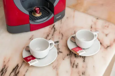 two cups on plates next to a toaster on a counter at OPO Bonjardim 902 II in Porto