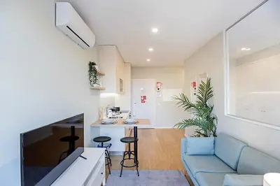 a living room with a blue couch and a kitchen at 31 Janeiro 157 - Charming 1BR Flat w/ AC & Balcony by LovelyStay in Porto