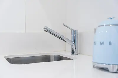 a stainless steel kitchen sink in a white kitchen at GuestReady - The Other Side in Porto
