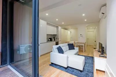 a living room with a white couch and a kitchen at Casinha da Formosa by Oporto Soul in Porto