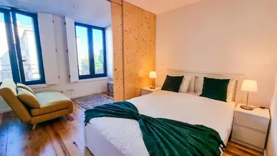 a bedroom with a bed and a chair and windows at Jardim do Morro Haus in Vila Nova de Gaia