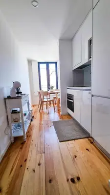 a kitchen with white cabinets and a wooden floor at Jardim do Morro Haus in Vila Nova de Gaia