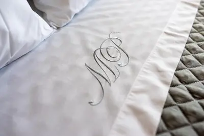 a letter on a bed with a white sheet at River 9 and City View Porto Gaia by MP in Vila Nova de Gaia