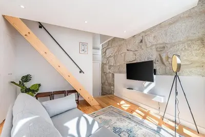 a living room with a couch and a tv at Cedofeita Balcony with Free Parking in Porto